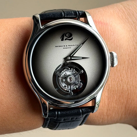 Luxury watch with black leather strap and visible mechanical components on a wrist.