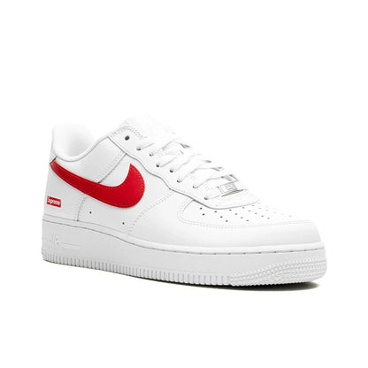 A white Nike Air Force 1 Low sneaker with a bright red Swoosh and a small red Supreme box logo on the heel, shown from a side profile on a white background.