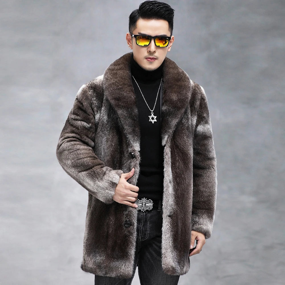 A man wearing a brown and gray faux fur coat over a black turtleneck, styled with sunglasses, a Star of David necklace, and jeans against a gray studio background.