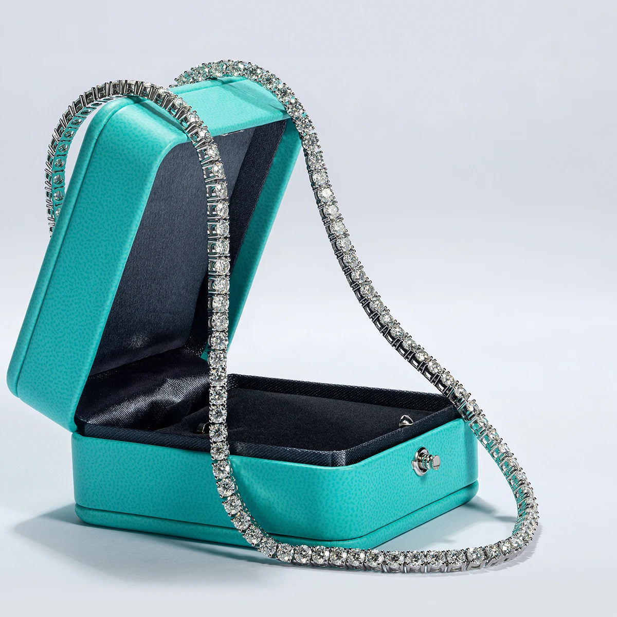 Turquoise jewelry box with a diamond-studded necklace on a light gray background