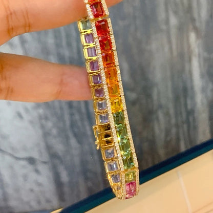 Multicolored gemstone bracelet held by a hand against a blurred background