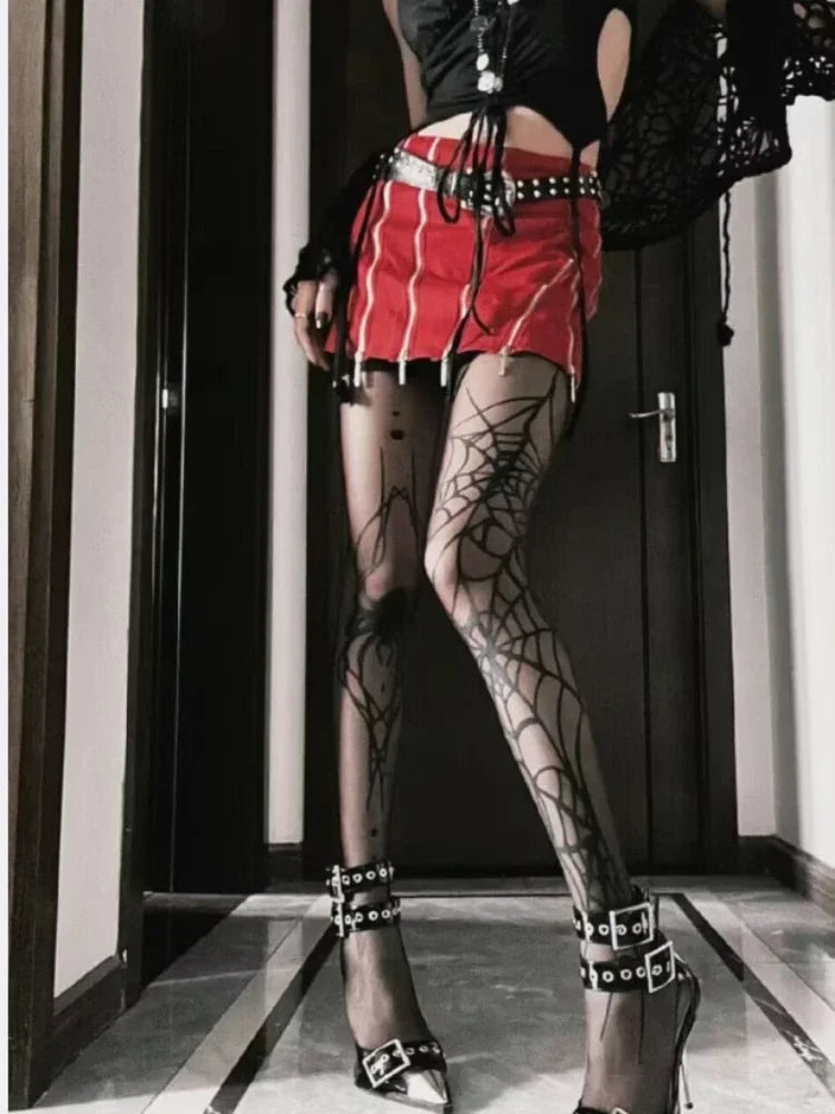 Person wearing a black top, red skirt, and spiderweb tights in a room.
