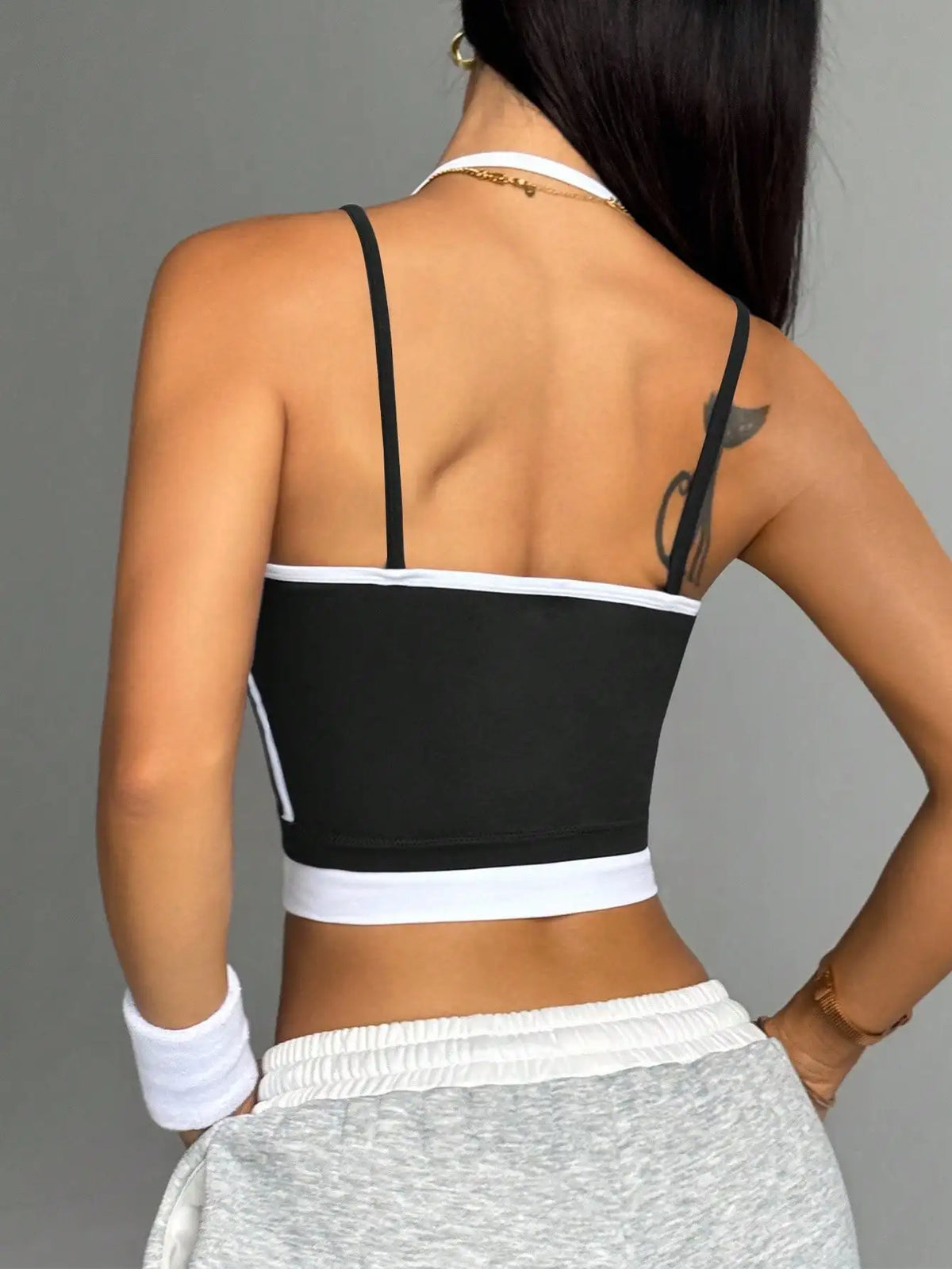 Person wearing a black and white sports bra with gray pants on a gray background
