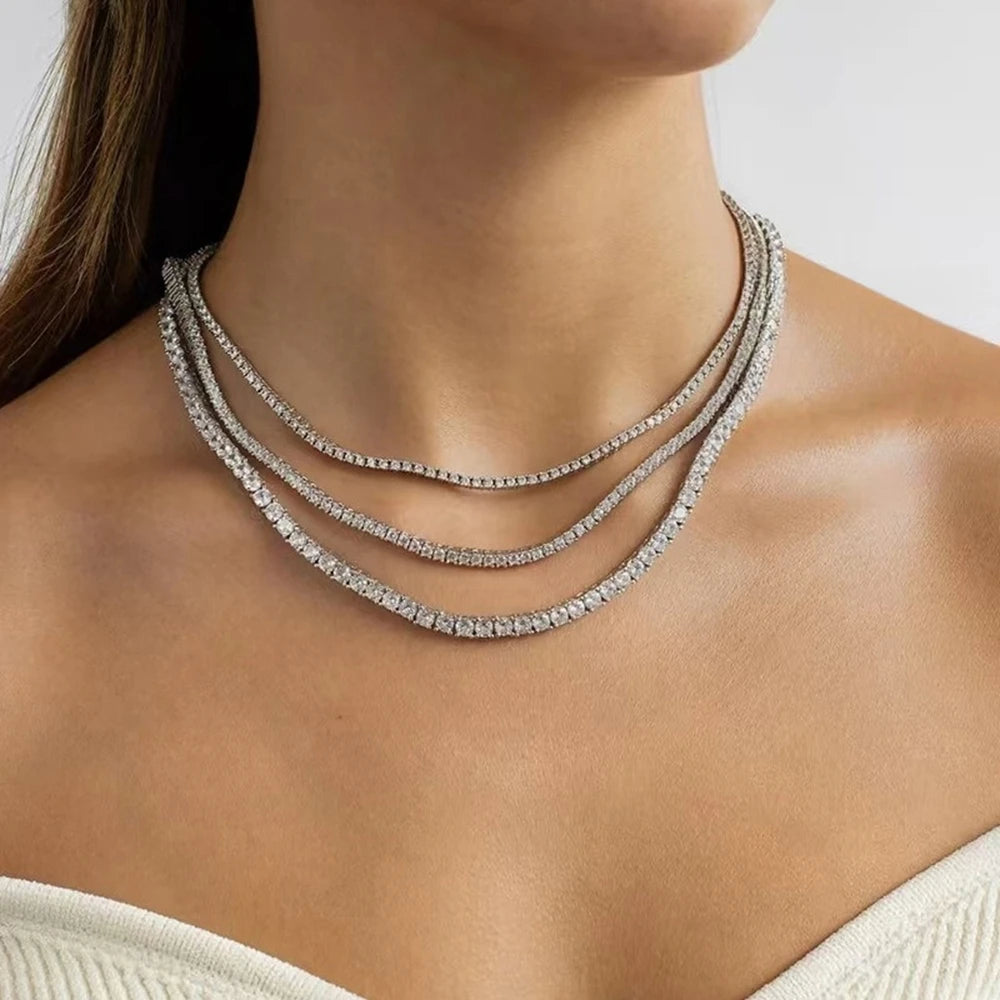 Close-up of a woman wearing a silver necklace with a plain background