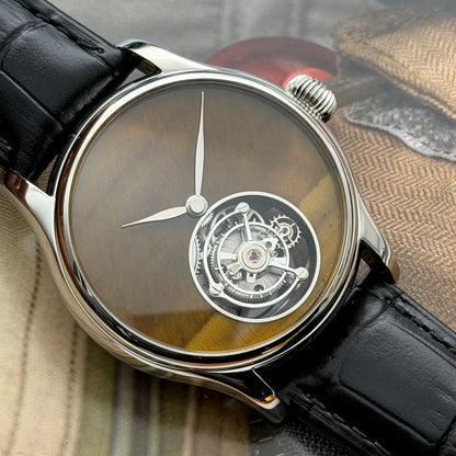 Luxury watch with black leather strap and intricate face design on a textured fabric background