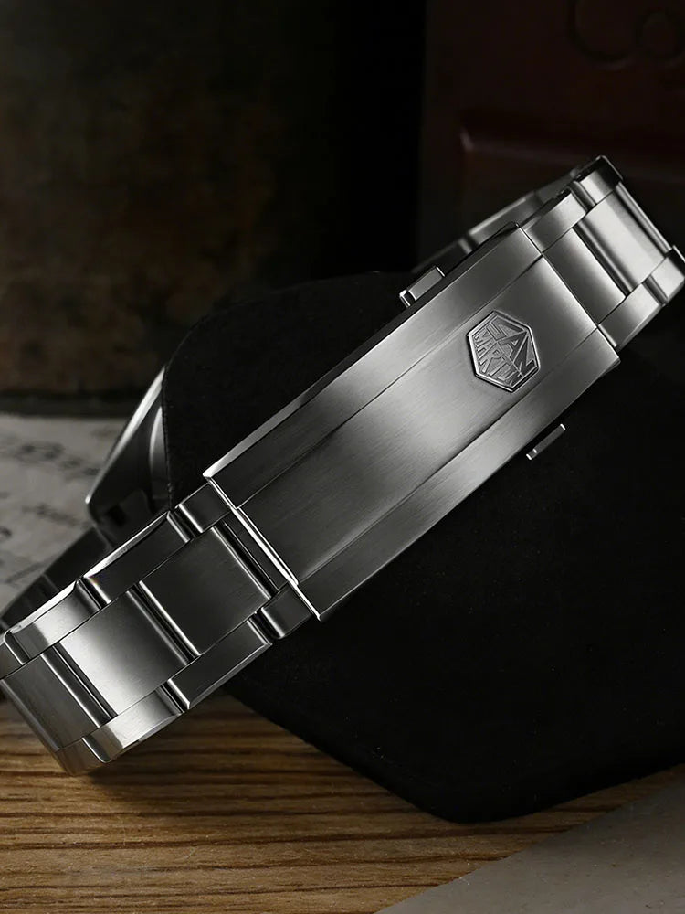 Close-up of a silver watch with a brand logo on a dark surface