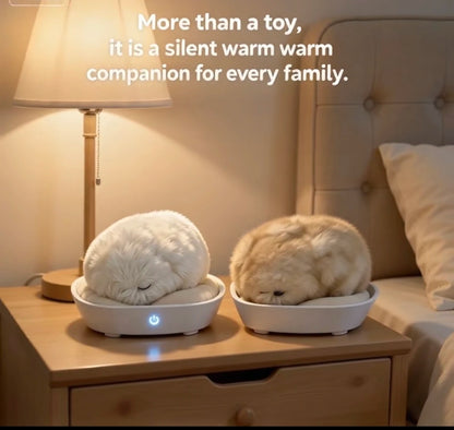 Two fluffy sleeping pets, one white and one cream, resting in white heated beds on a wooden nightstand beside a lit lamp and bed. Text at the top reads, 'More than a toy, it is a silent warm companion for every family.