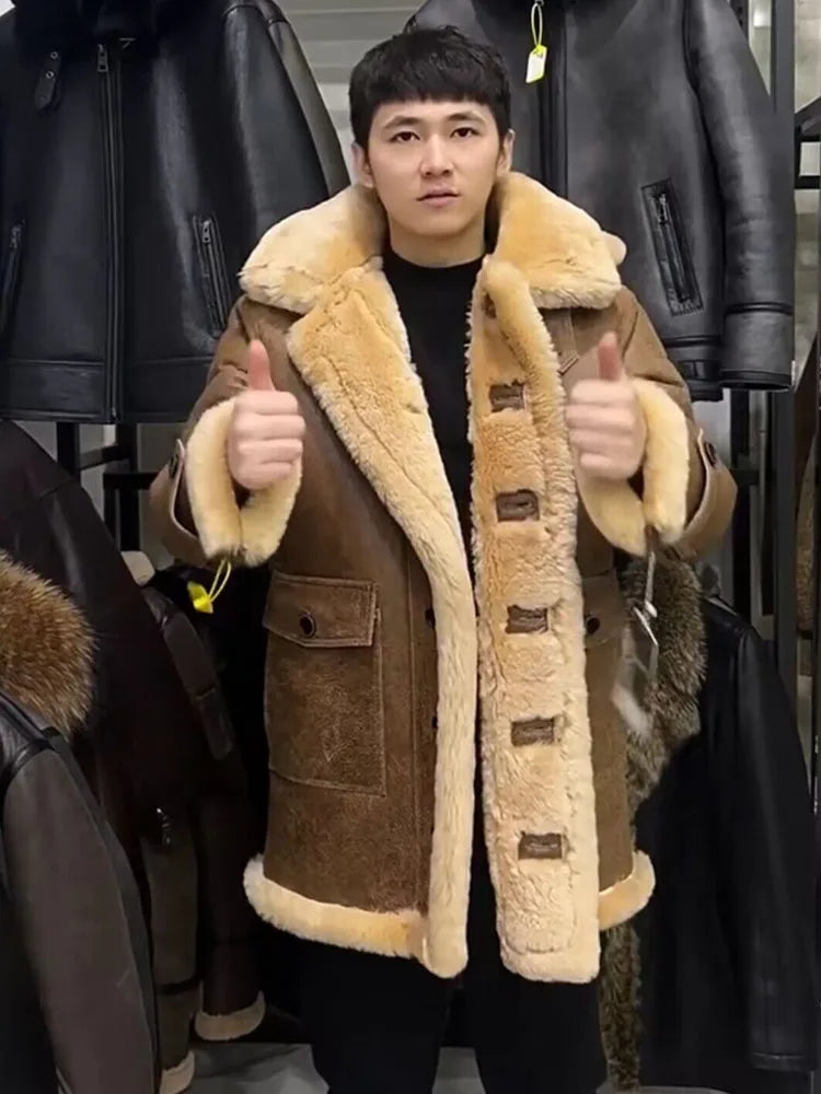 A man wearing a brown shearling-lined coat with a beige collar and cuffs, standing in front of a display of black leather jackets and giving a thumbs-up with both hands.