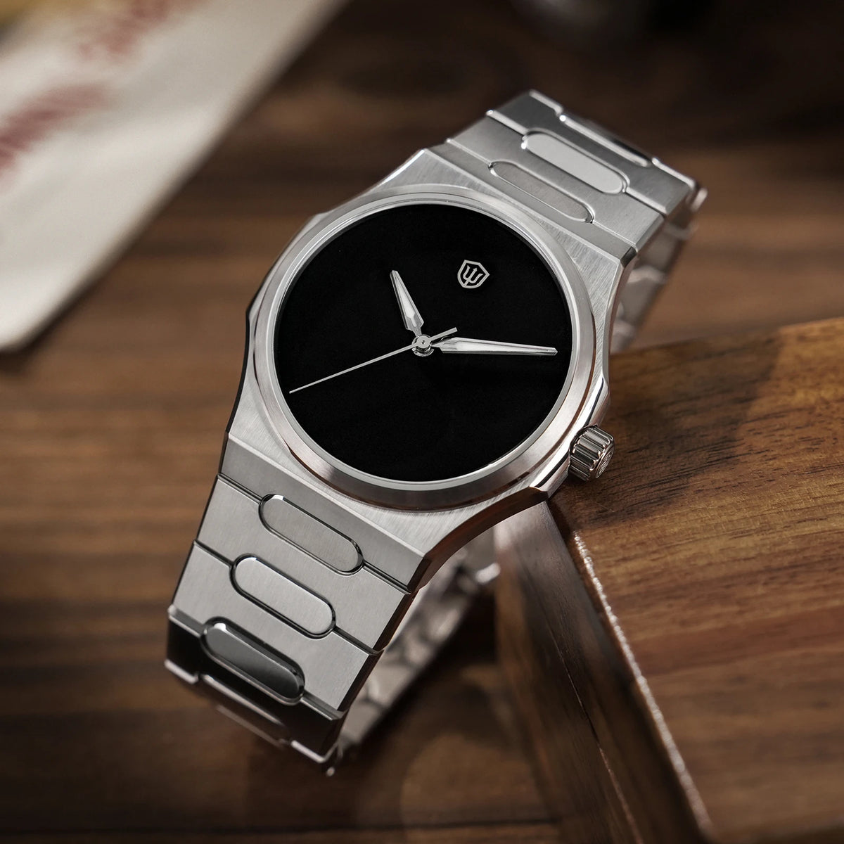 Silver watch with black face on a wooden surface