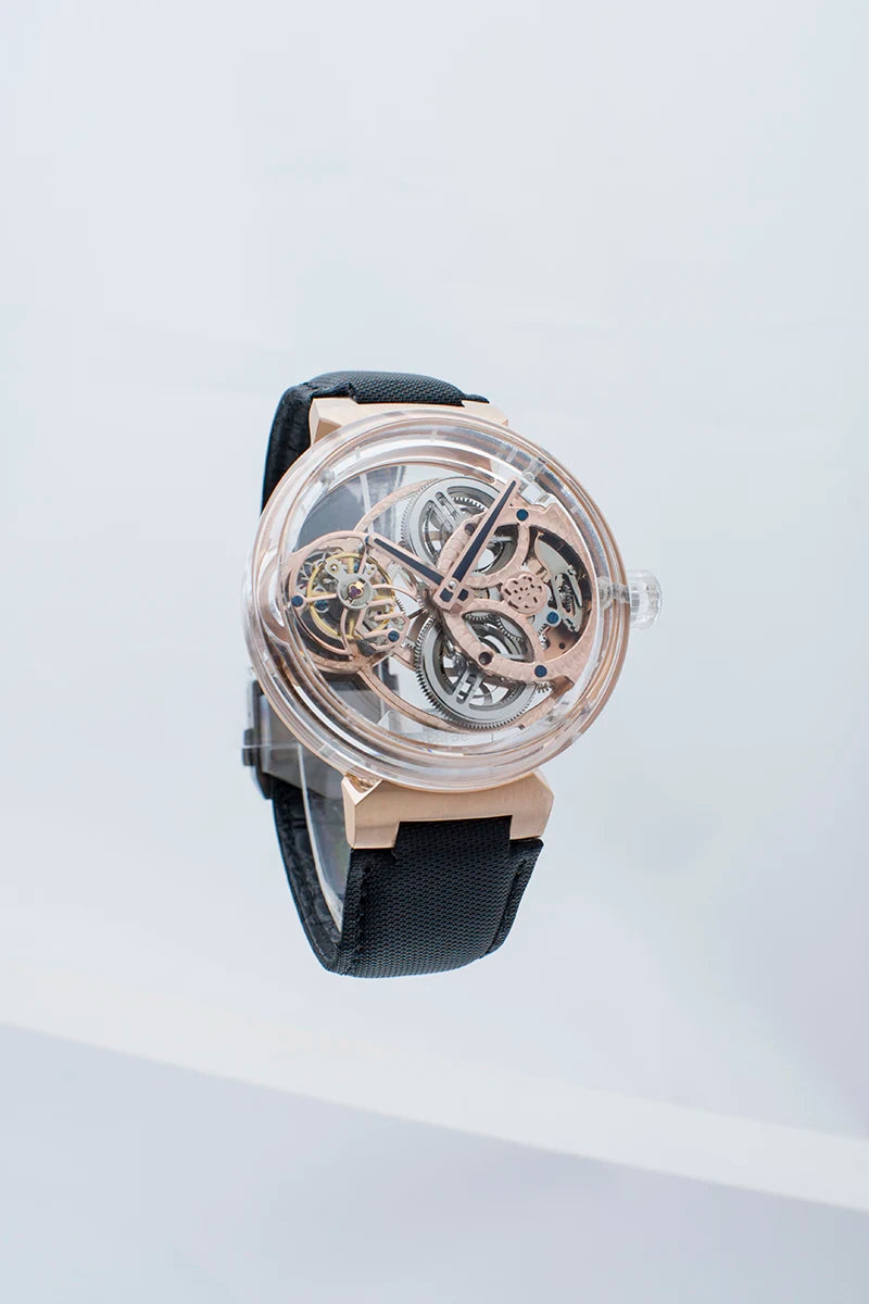 A skeleton watch with a rose gold-tone case and visible mechanical gears, paired with a black strap, shown against a clean white background.