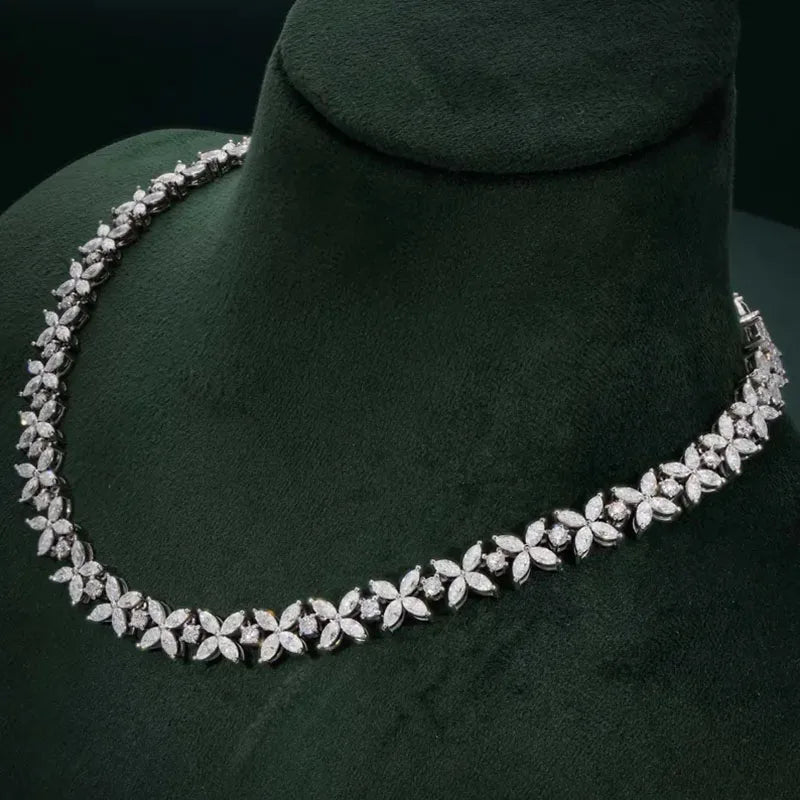 Silver necklace with floral design on a green mannequin bust