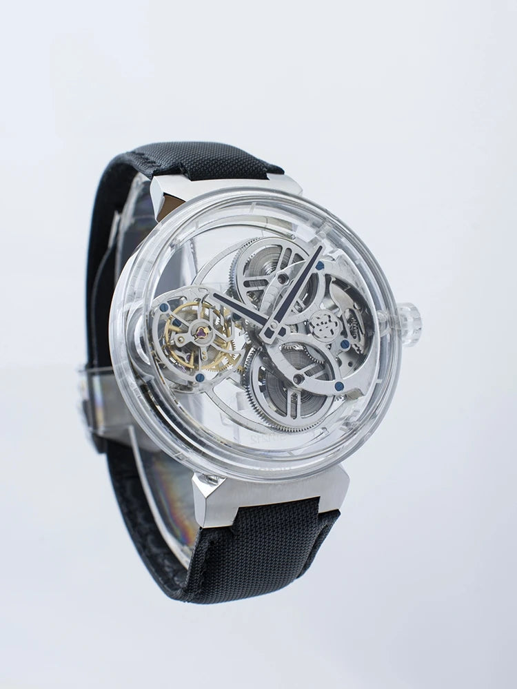 A skeleton watch with a clear circular case showing a detailed mechanical movement, a black textured strap, and silver-toned case hardware, photographed against a clean white background.