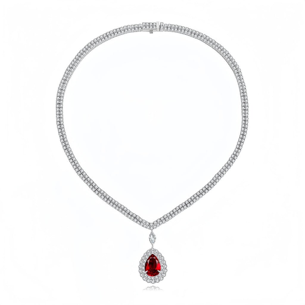 A silver-toned diamond necklace with a teardrop-shaped red gemstone pendant, displayed on a clean white background.