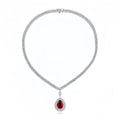 A silver-toned diamond necklace with a teardrop-shaped red gemstone pendant, displayed on a clean white background.