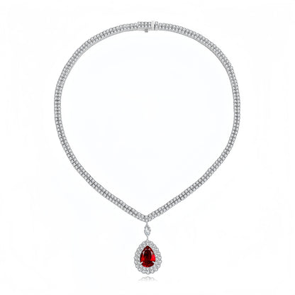 A silver-toned diamond necklace with a teardrop-shaped red gemstone pendant, displayed on a clean white background.