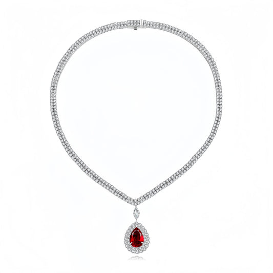 A silver-toned diamond necklace with a teardrop-shaped red gemstone pendant, displayed on a clean white background.