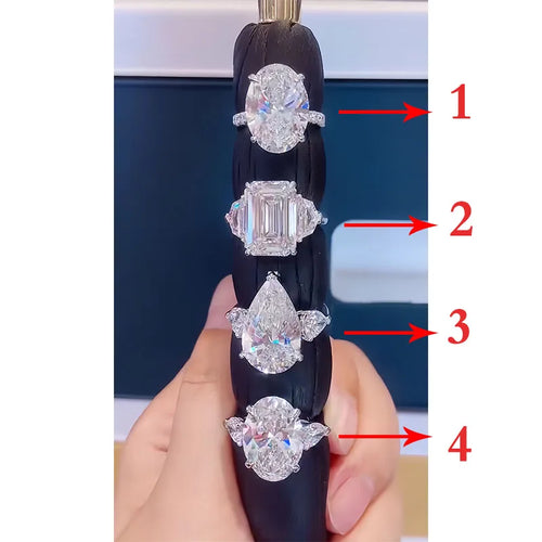 Diamond ring with four different diamond shapes held by a hand against a blurred background.