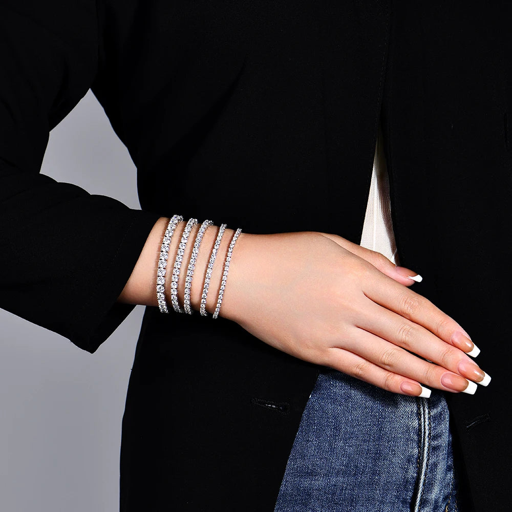 Person wearing multiple silver bracelets on a black background
