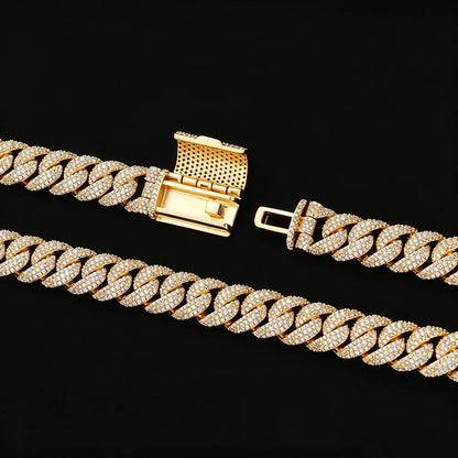 A gold-toned Cuban link chain bracelet paved with clear cubic zirconia stones, shown in two overlapping sections on a solid black background, highlighting the clasp and the detailed stone setting.