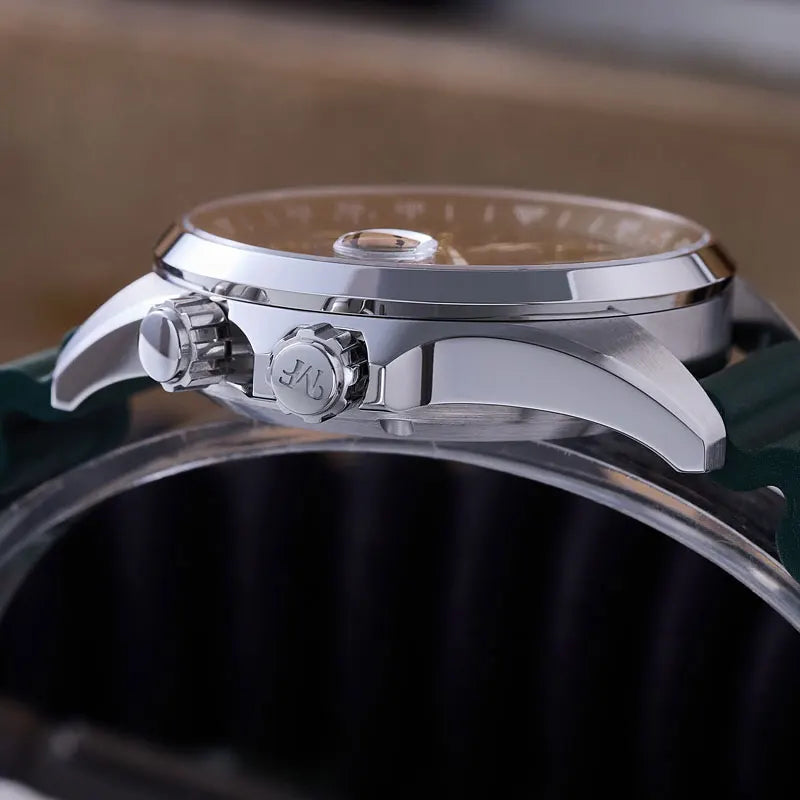 Close-up side view of a silver-toned wristwatch with a polished metal case, textured crown details, and a dark green strap resting on a clear display stand.