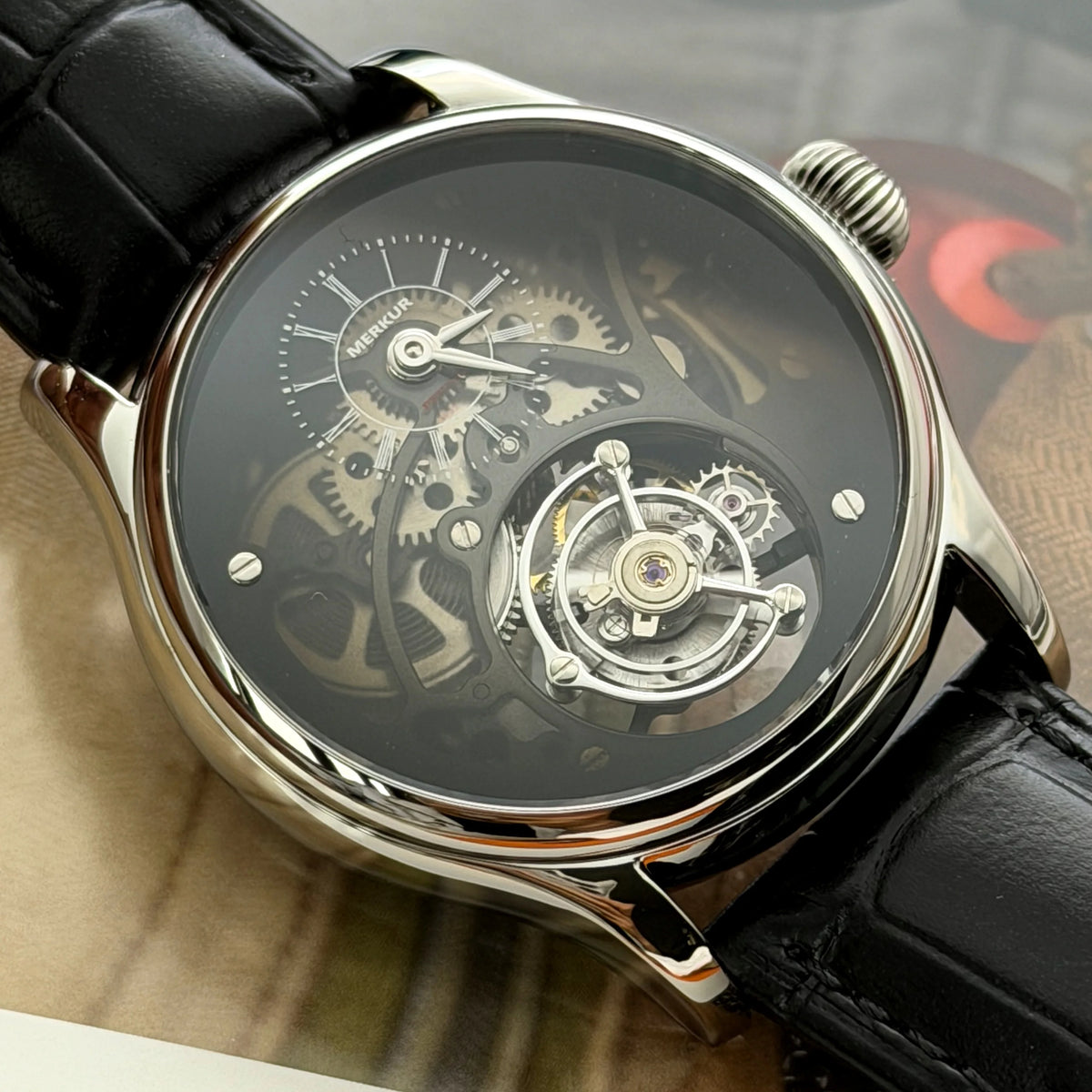 Close-up of a mechanical watch with a black strap on a blurred background