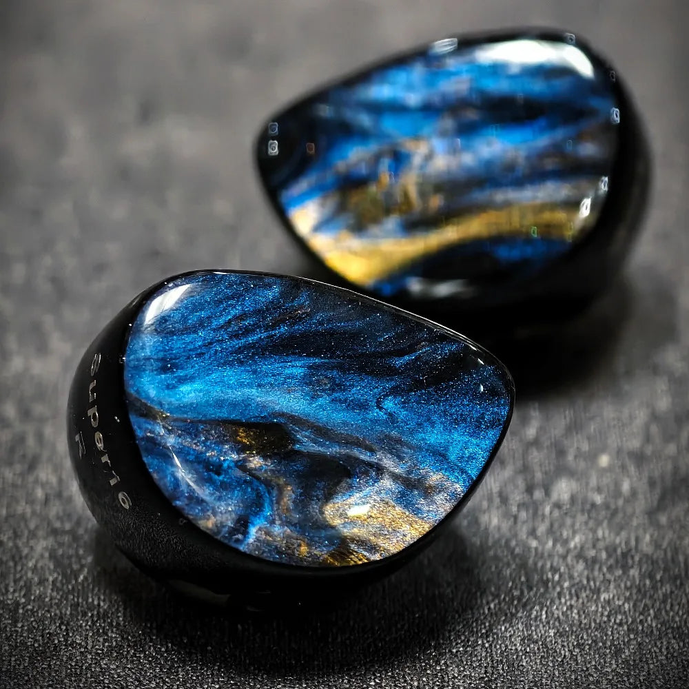 Two blue marbled stones on a dark textured surface
