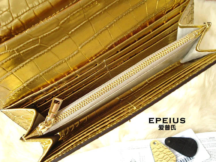 Close-up of a gold-toned crocodile-embossed wallet or card case opened to show interior compartments and a zippered pocket, with the brand name EPEIUS printed on the surface.