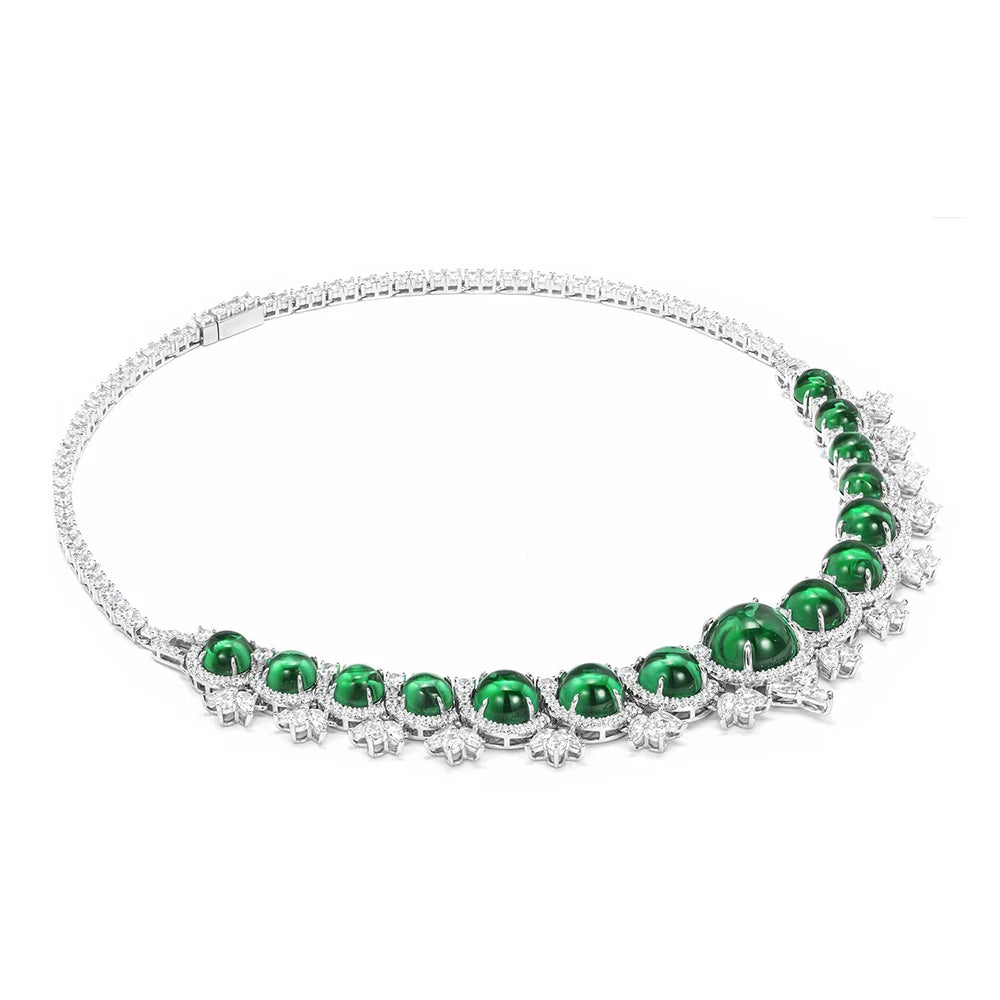A silver-toned tennis necklace featuring a row of oval-cut emerald green gemstones and small clear stones, displayed on a clean white background.