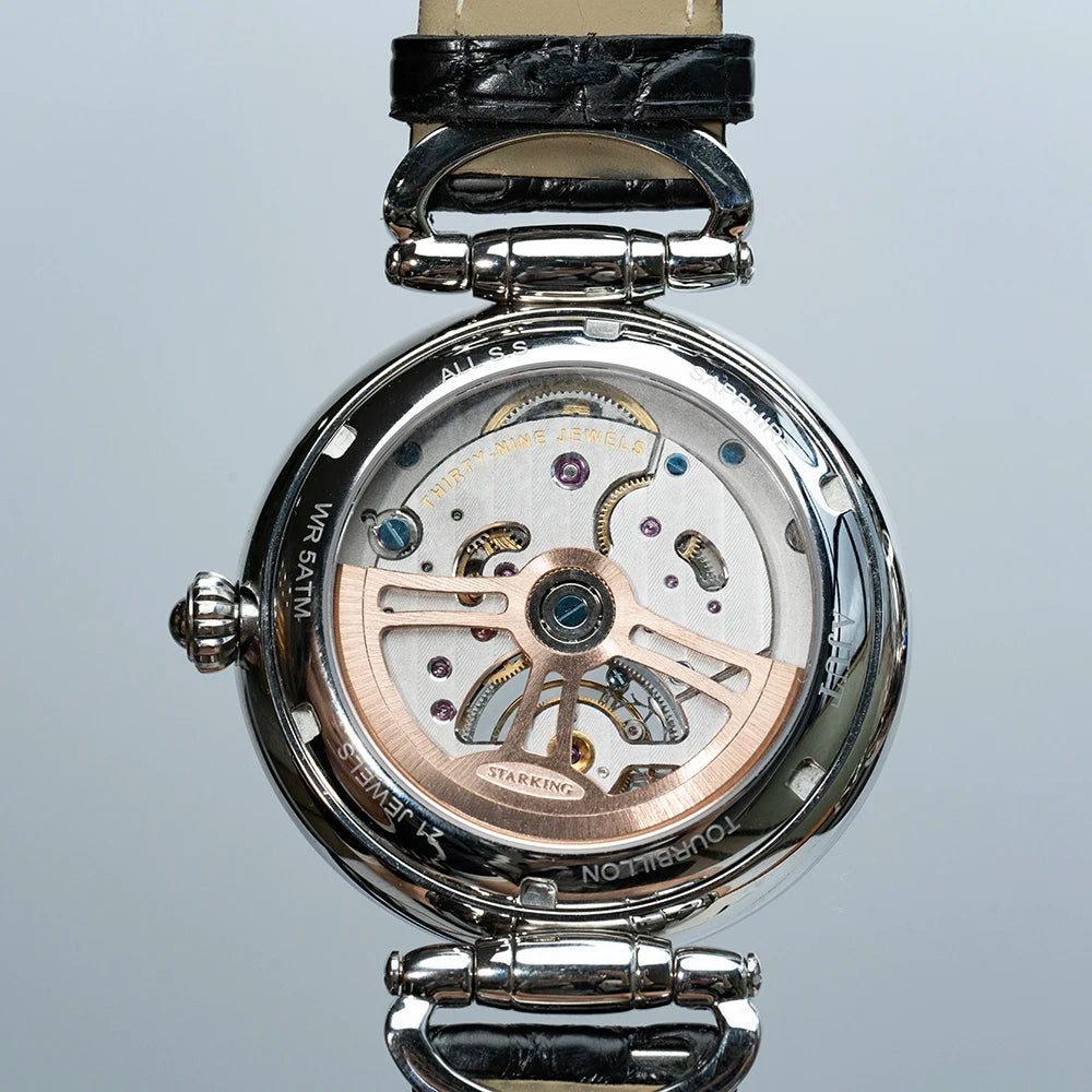 Close-up of a mechanical watch with visible brand name on a light gray background