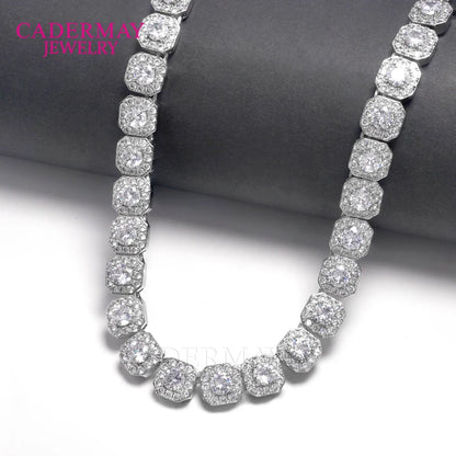 A silver-toned pave-set necklace with round and cushion-cut clear stones, displayed on a dark gray cylindrical stand against a white background. The brand name 'CADERMAY JEWELRY' is visible in pink text in the upper left corner.