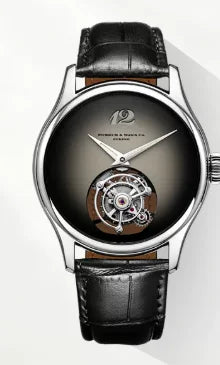 A luxury wristwatch with a round silver-tone case, a dark gradient dial, a visible tourbillon movement through the lower dial, and a black leather strap.