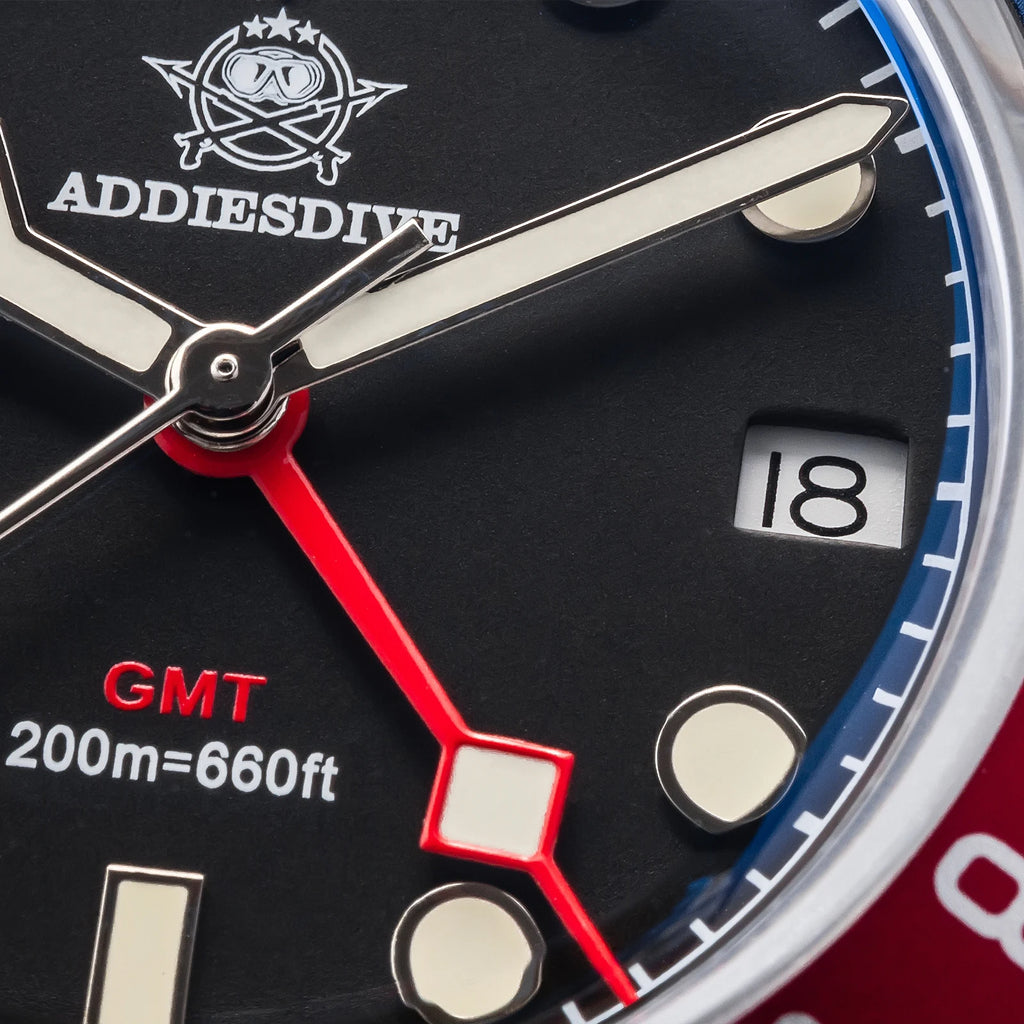 Close-up of a watch face with Addies Dive logo and GMT indication.