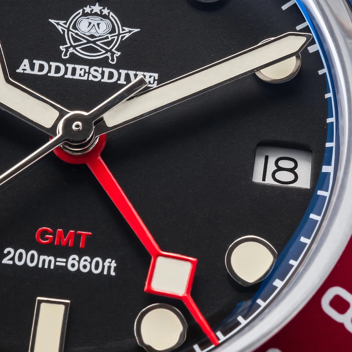 Close-up of a watch face with Addies Dive logo and GMT indication.