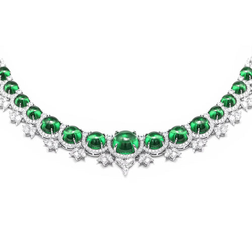 A silver-toned necklace featuring a row of oval-cut emerald green gemstones, each surrounded by small clear stones in starburst and round settings, photographed on a plain white background.