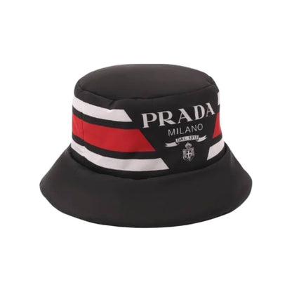 A black bucket hat featuring a prominent band with red and white stripes and white 'PRADA MILANO' branding, set against a plain white background.