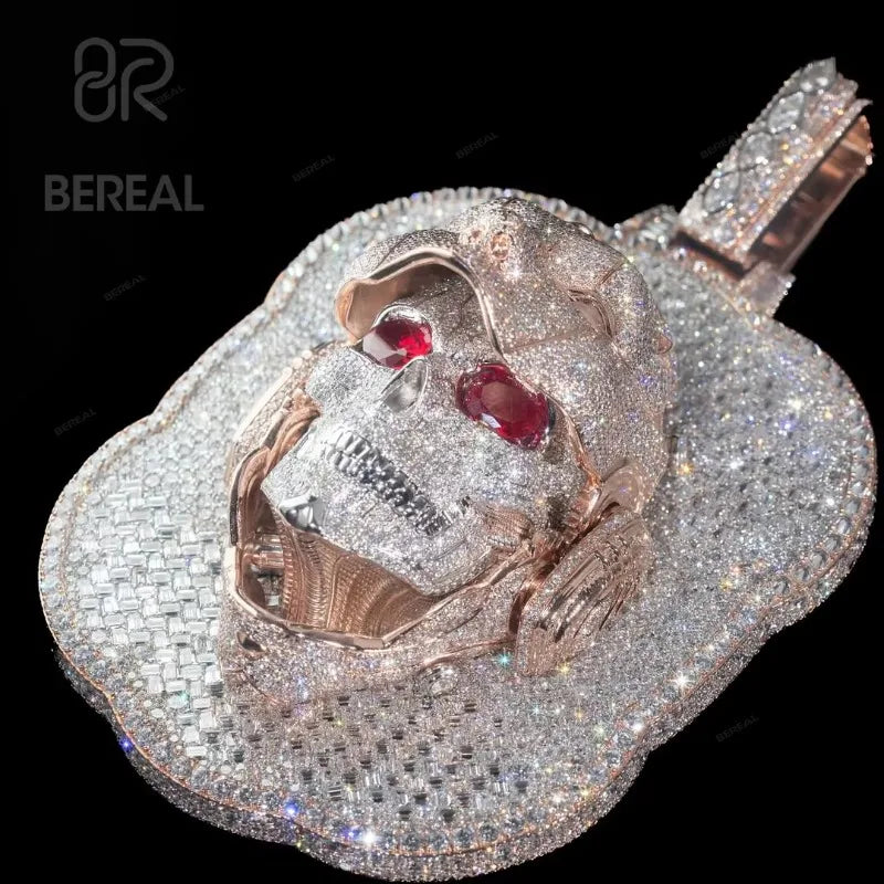 A skull-shaped pendant covered in sparkling clear stones, with two red gemstone eyes and a rose gold-toned skull core, shown on a black background. The BEREAL logo is visible in the upper left.