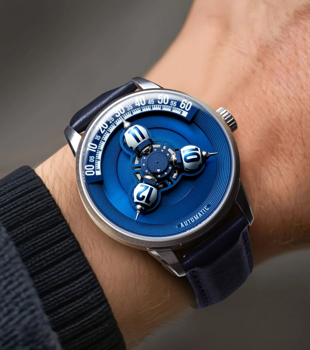 A close-up of a wrist wearing a luxury automatic watch with a vibrant blue dial, silver-toned case, and dark blue leather strap.